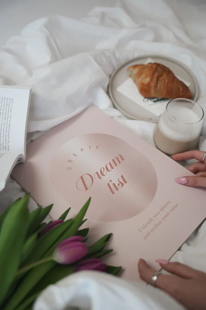 Rózsaszín borítású Manifestshop Dream List füzet „Unleash your talents and realize your value” felirattal.